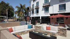 A hotel with outdoor seating, a pool, and a stone wall. - Fairfield Inn & Suites by Marriott Camarillo (Camarillo)