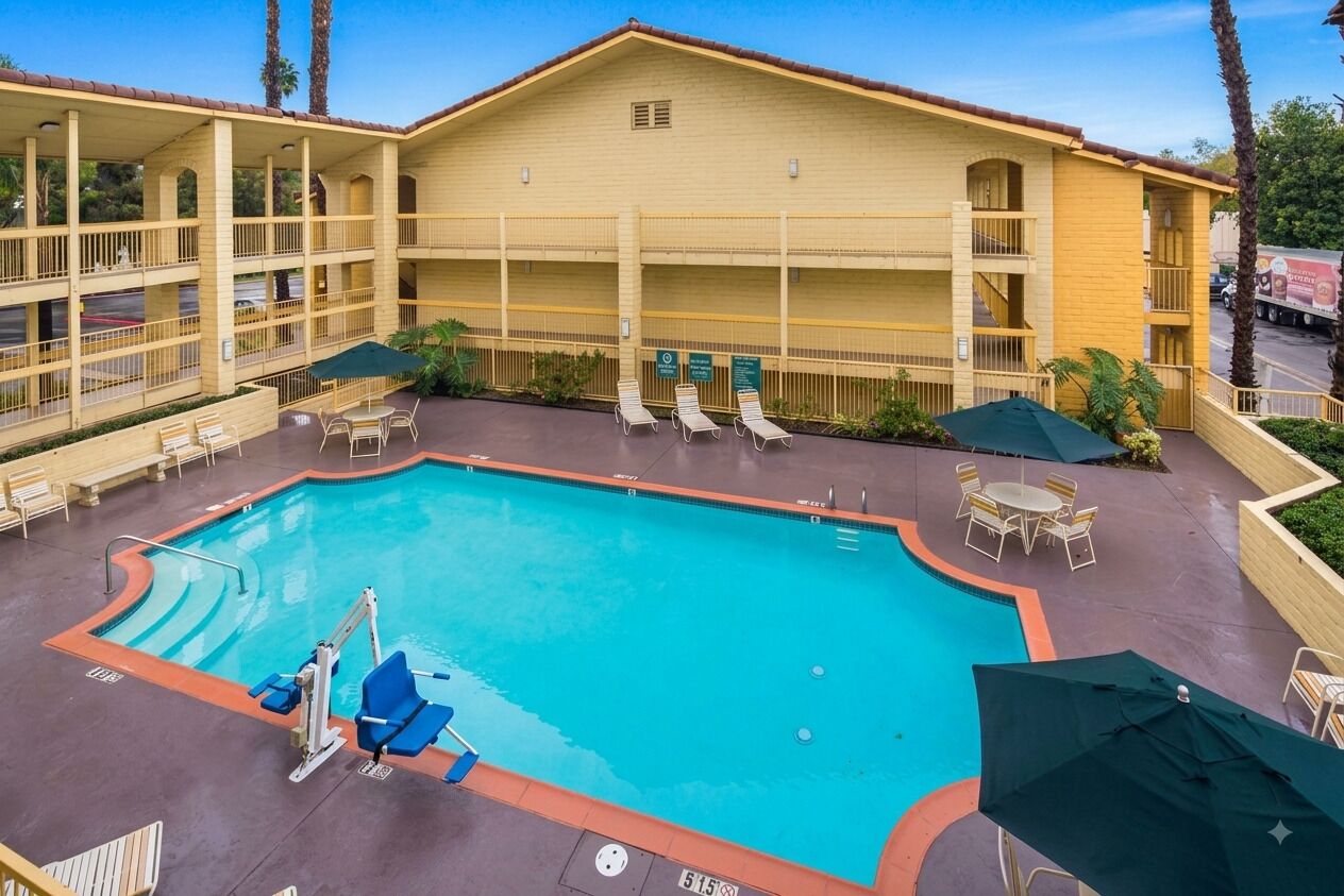A hotel with a pool, outdoor seating, and a multi-story building.