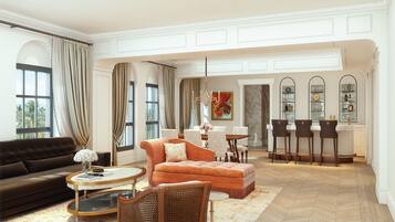 Amplia sala de estar con sofá, sillón y reposapiés, un comedor con sillas y mesa, y una zona de bar con taburetes.