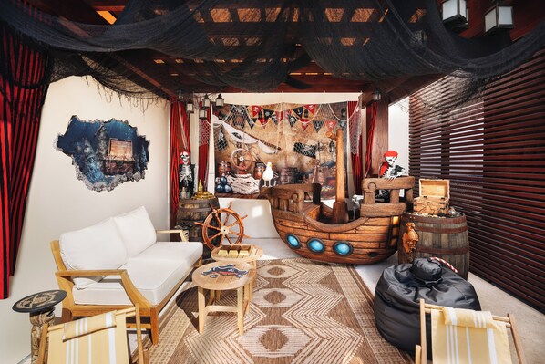 A cozy outdoor seating area with a wooden boat decoration, a white sofa, and a patterned rug.