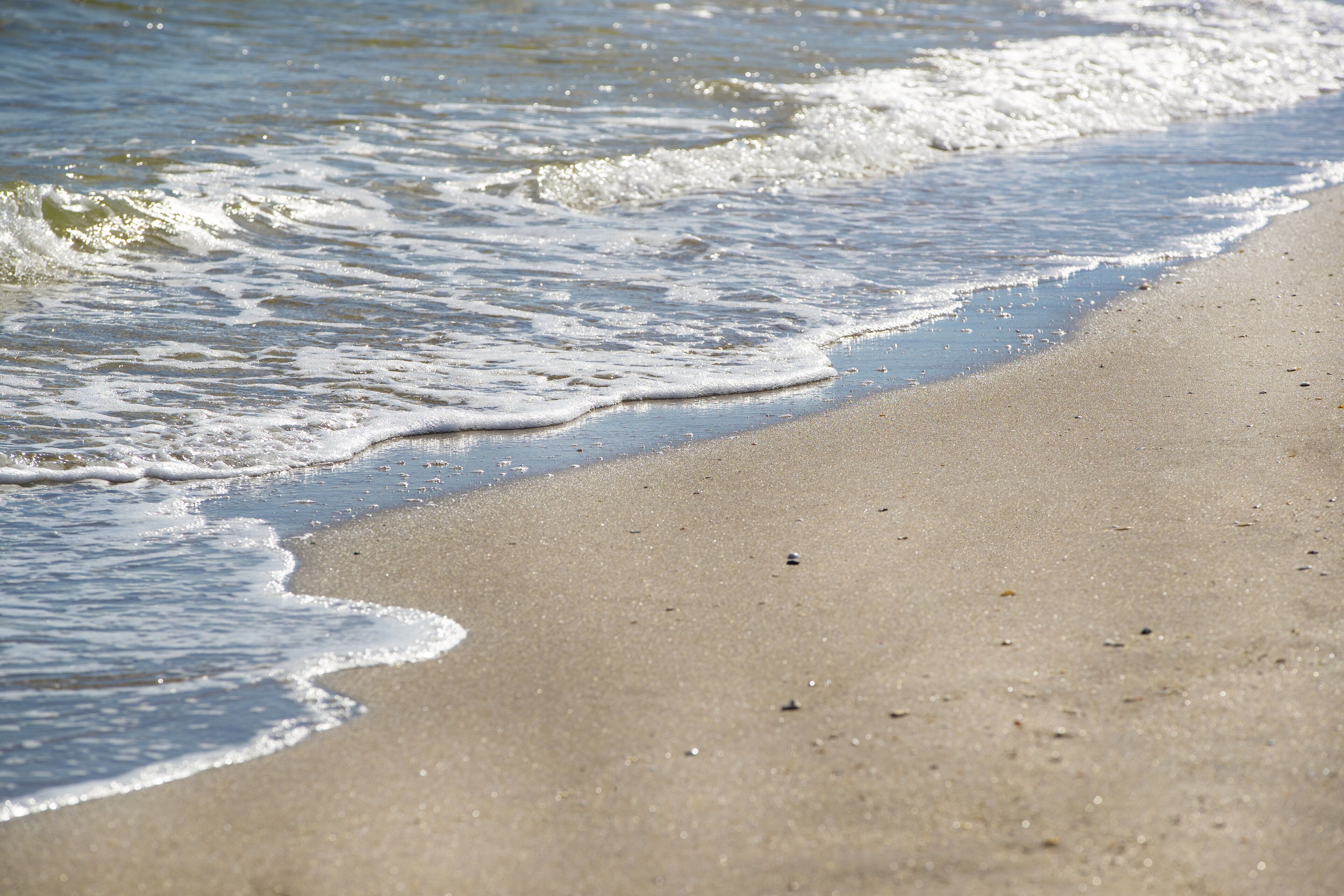 A sandy beach with gentle waves lapping at the shore.