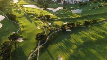 Players can enjoy a serene golfing experience surrounded by lush greenery and palm trees.