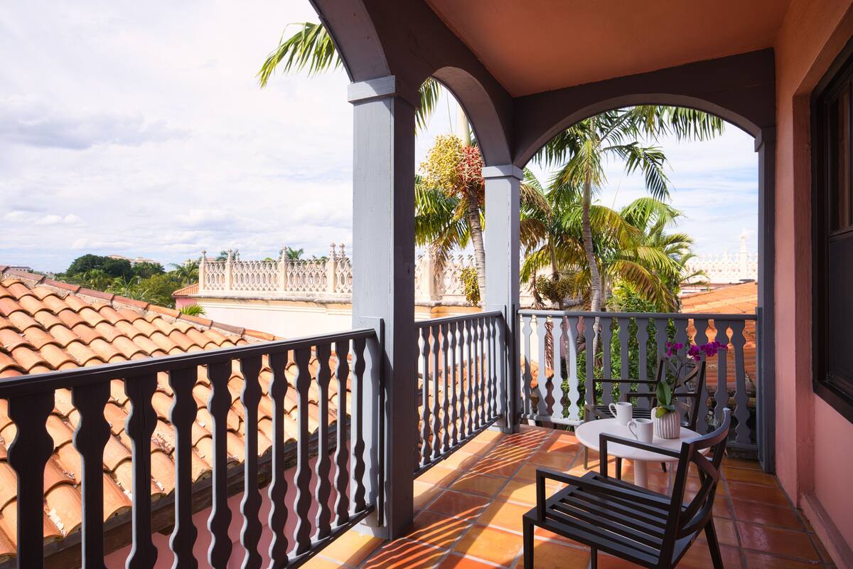 A balcony with a tiled floor, a table with chairs, and a railing.