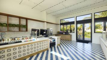 A modern kitchen area with a counter displaying various food items, a coffee machine, and a refrigerator.
