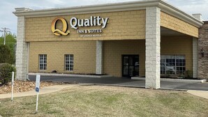 Un hotel llamado "Quality Inn & Suites by Choice Hotels" con fachada de ladrillo color beige y un gran logo con la letra "Q".