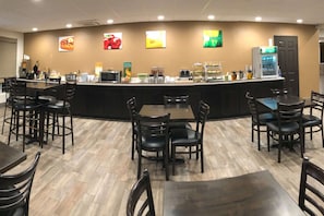 A restaurant with a counter, chairs, tables, and a vending machine. - Quality Inn & Suites Paragould (Paragould)