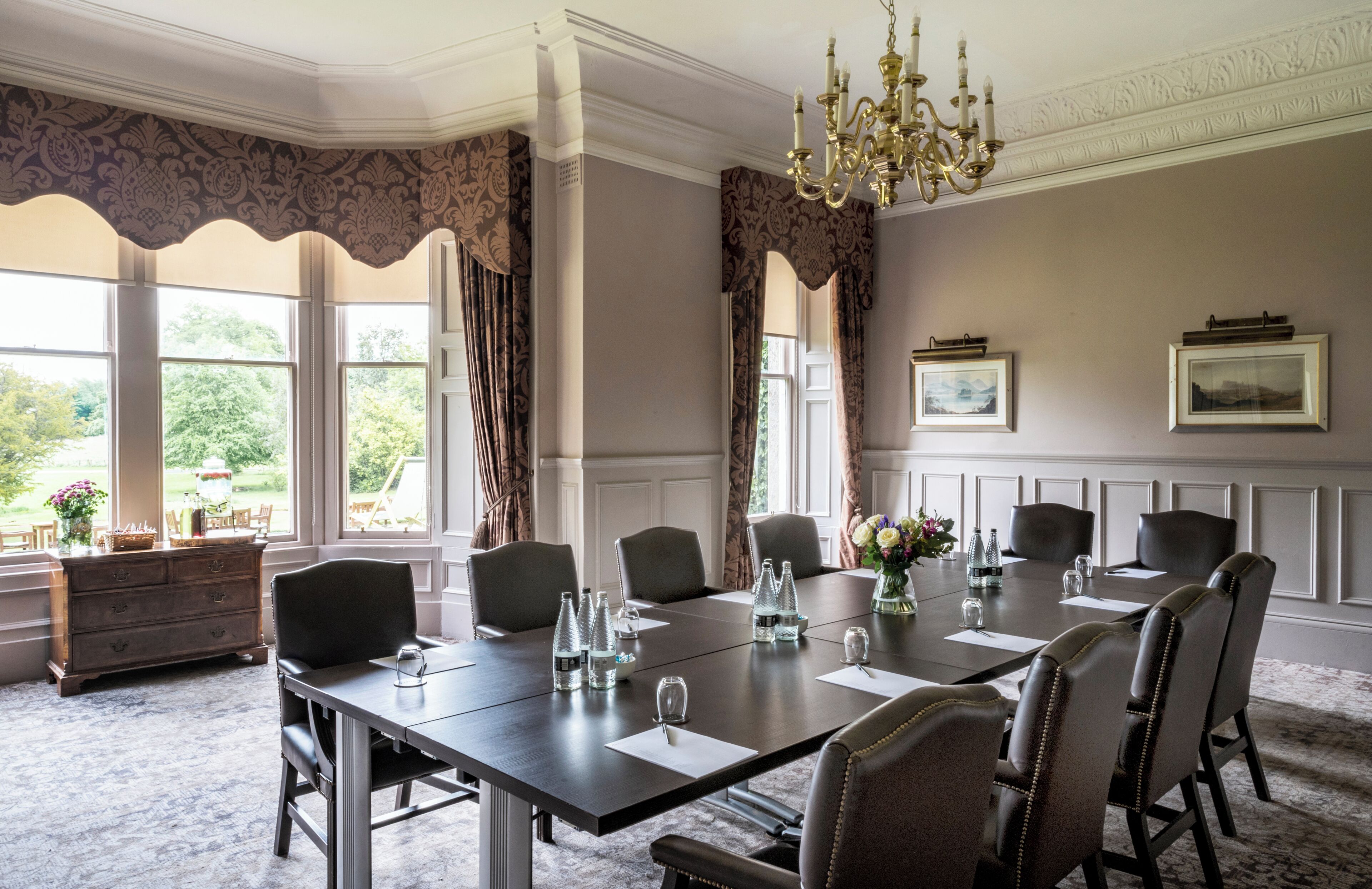 A formal meeting room with a long table, chairs, and a chandelier.