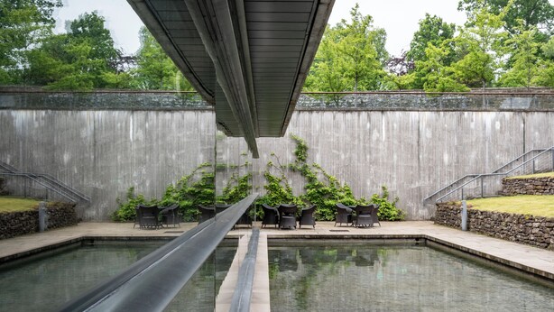 A pool with a slide, outdoor seating, and a stone wall.