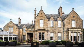 A historic stone building with multiple gabled roofs, large windows, and a conservatory.