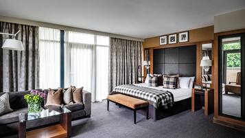 A hotel room with a bed, a sofa, a coffee table, and a large window with curtains.