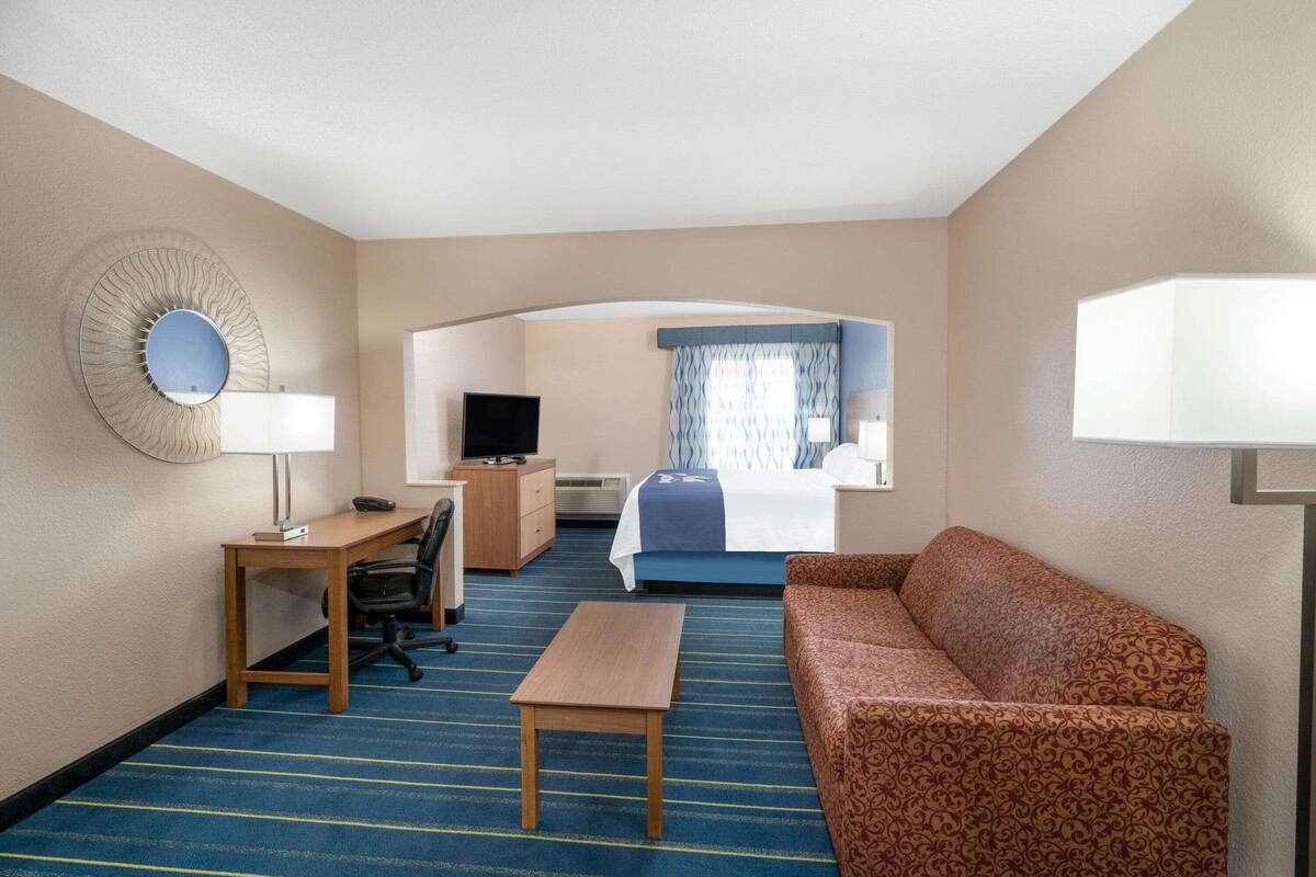 A hotel room with a bed, a desk with a chair, a sofa, and a television.