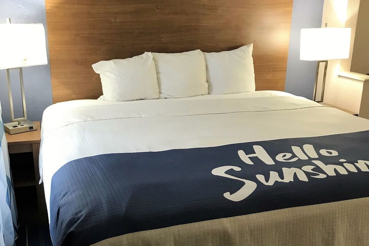 Une chambre d’hôtel avec un lit, deux lampes de chevet, une table de chevet et un luminaire fixé au mur.