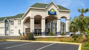 Un bâtiment Days Inn & Suites doté d’une architecture moderne, avec une entrée imposante surmontée d’une auge arquée et d’une enseigne placée au-dessus de l’entrée.