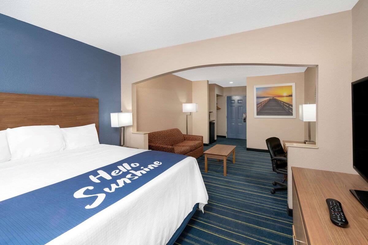 A hotel room with a bed, a desk, a chair, and a TV.