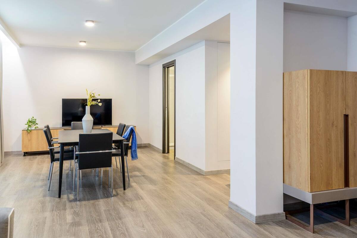 A modern room with a dining table, chairs, a TV, and a wooden cabinet.