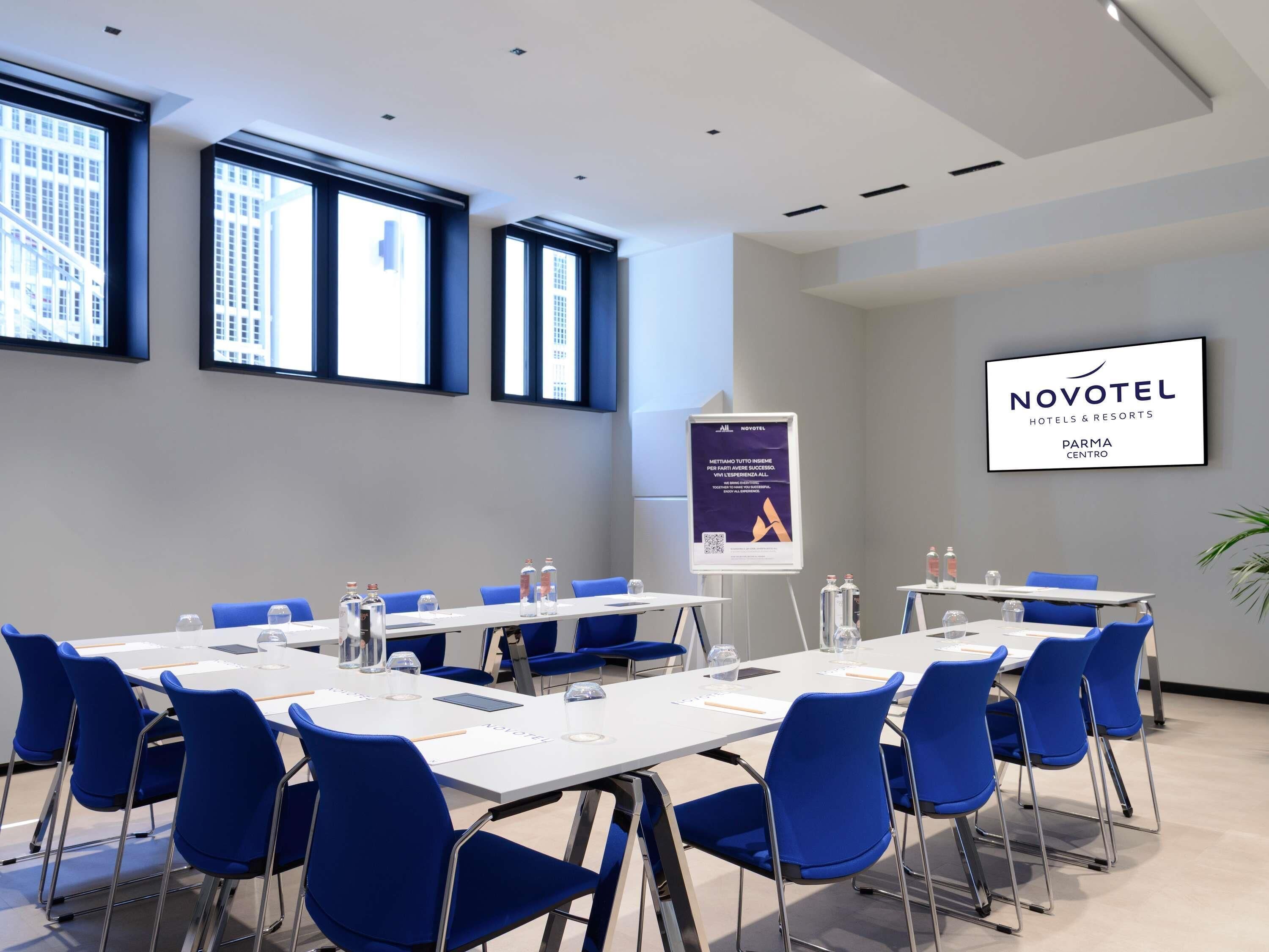Un salón de conferencias con mesas, sillas y el letrero de Novotel.