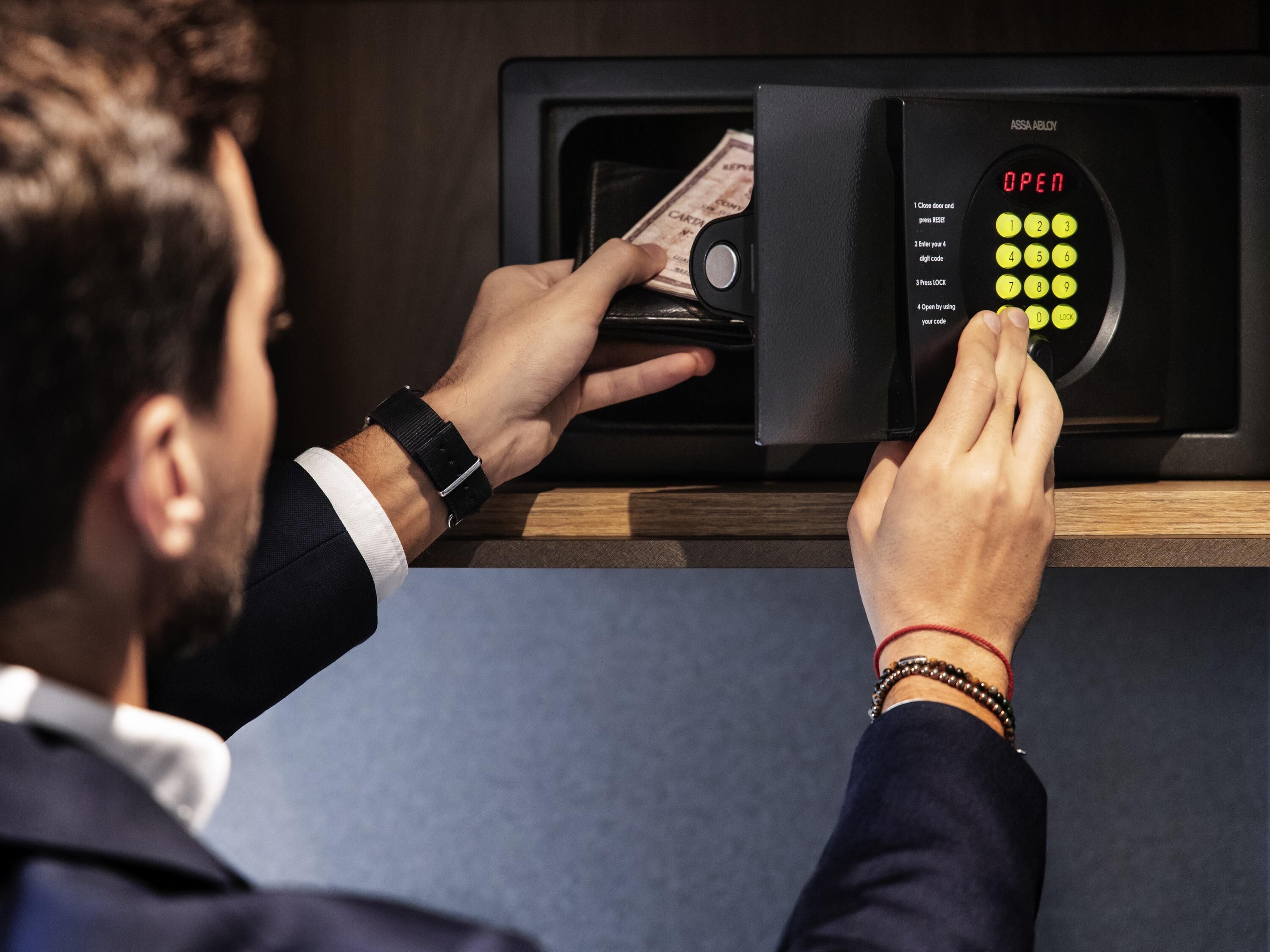 A person using a digital safe with a keypad and a display that reads "OPEN".