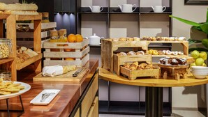 A breakfast buffet with various pastries, fruits, and a coffee station.