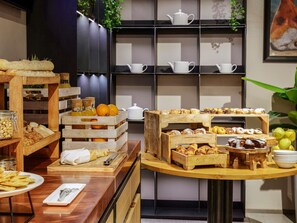 Ein reichhaltiges Frühstücksbuffet mit Gebäck, Früchten und einer Kaffeestation.