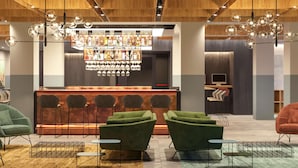 A bar area with a variety of bottles and glasses, green upholstered chairs, and a modern ceiling design.