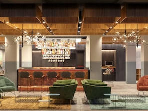 A bar area with a variety of bottles and glasses, green upholstered chairs, and a modern ceiling design. - Novotel Parma Centro (Parma)