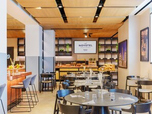 A modern hotel lobby with a reception desk, seating area, and a buffet. - Novotel Parma Centro (Parma)