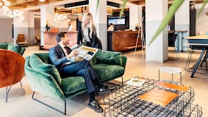 A modern interior with a green sofa, a metal coffee table, and a wooden reception desk.