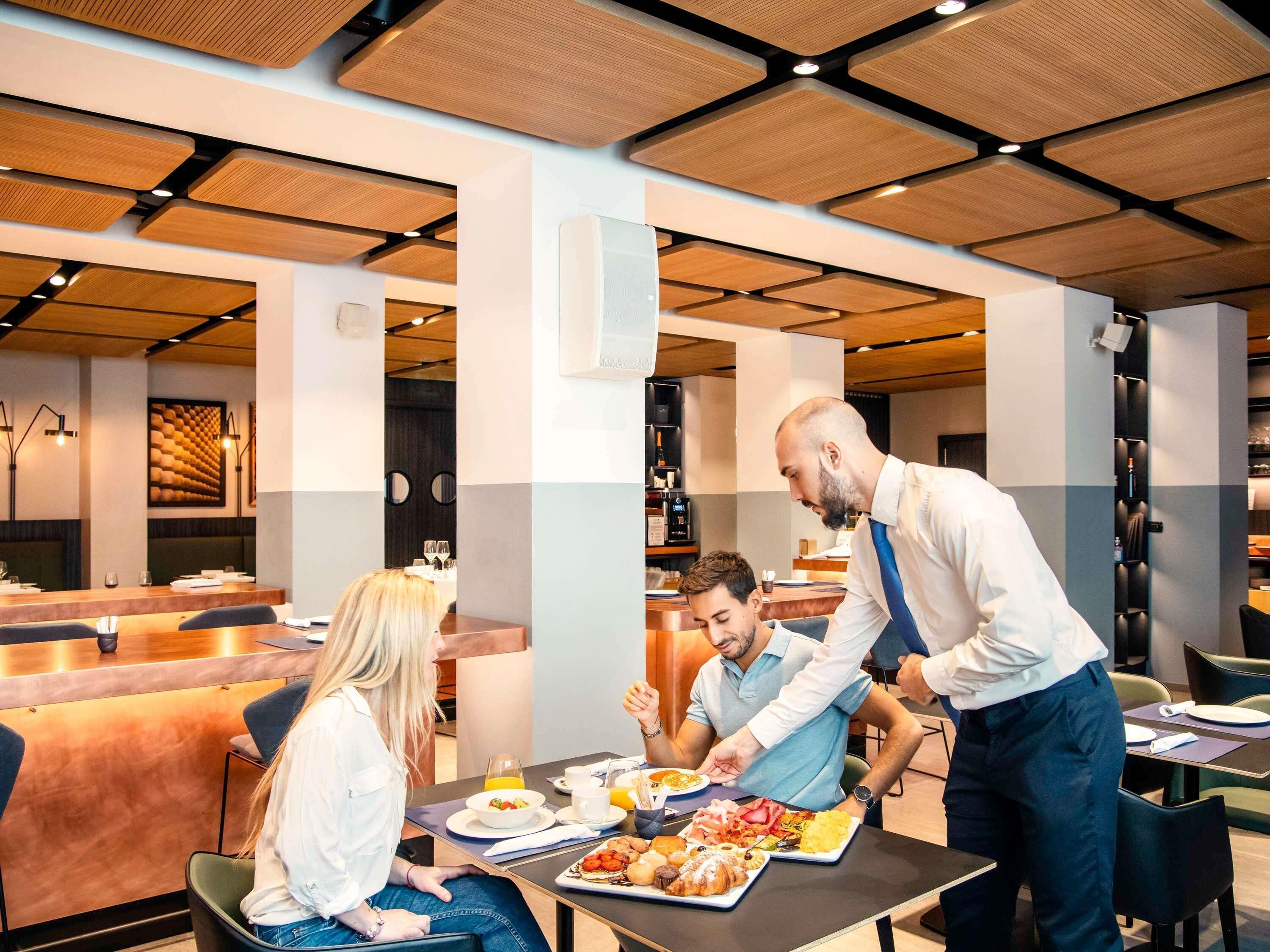 Een moderne eetruimte met een houten plafond, een toonbank en een buffet met diverse gerechten.