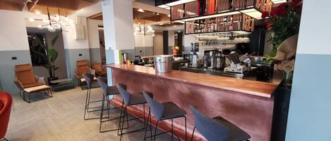 A modern bar area with a copper counter, bar stools, and a variety of bar equipment.