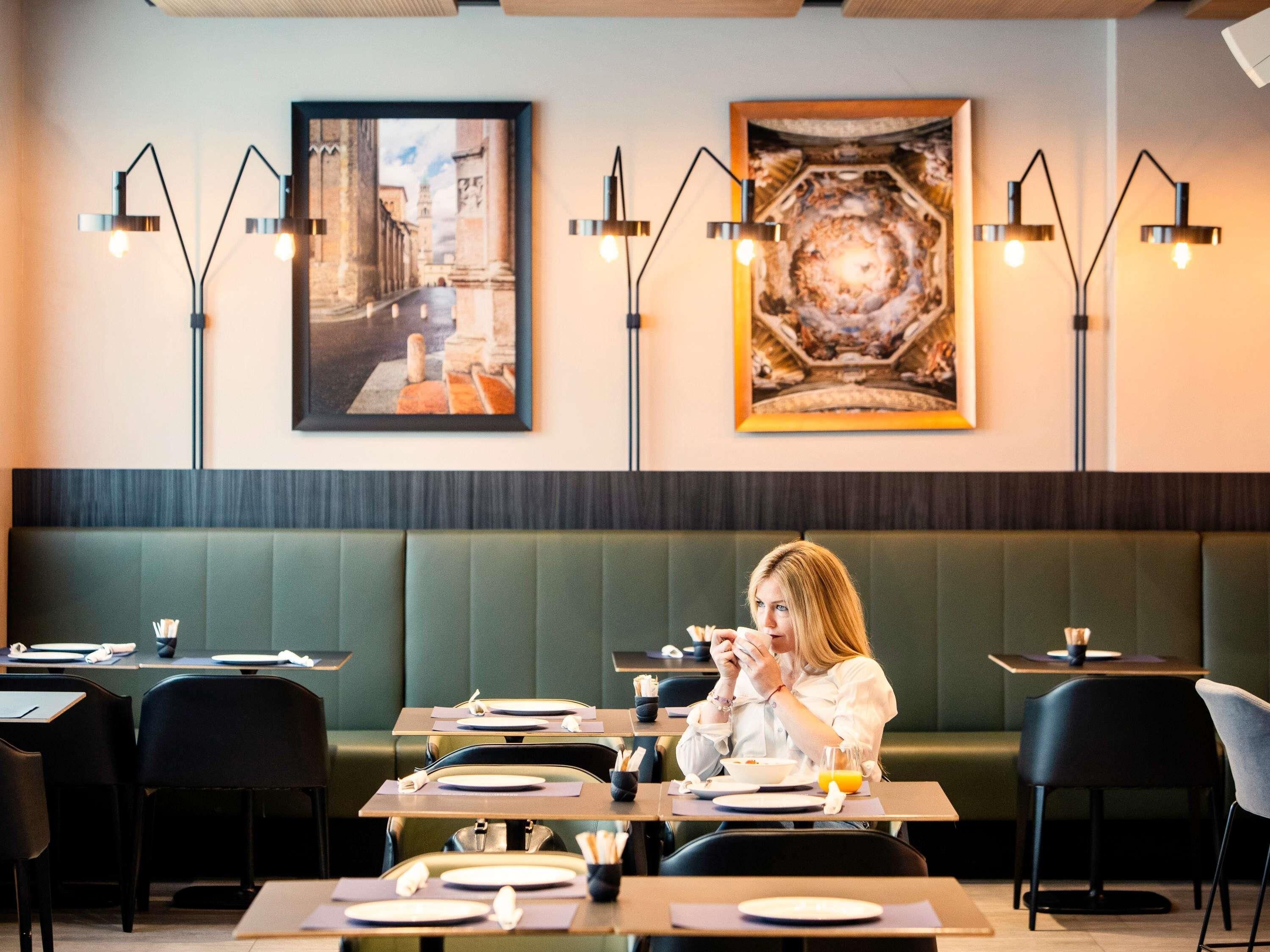 Un restaurante con cabinas, mesas y lámparas de iluminación moderna.