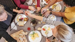 A group of people dining at a table with various dishes, utensils, and bread. - ibis Brussels Airport (Machelen)