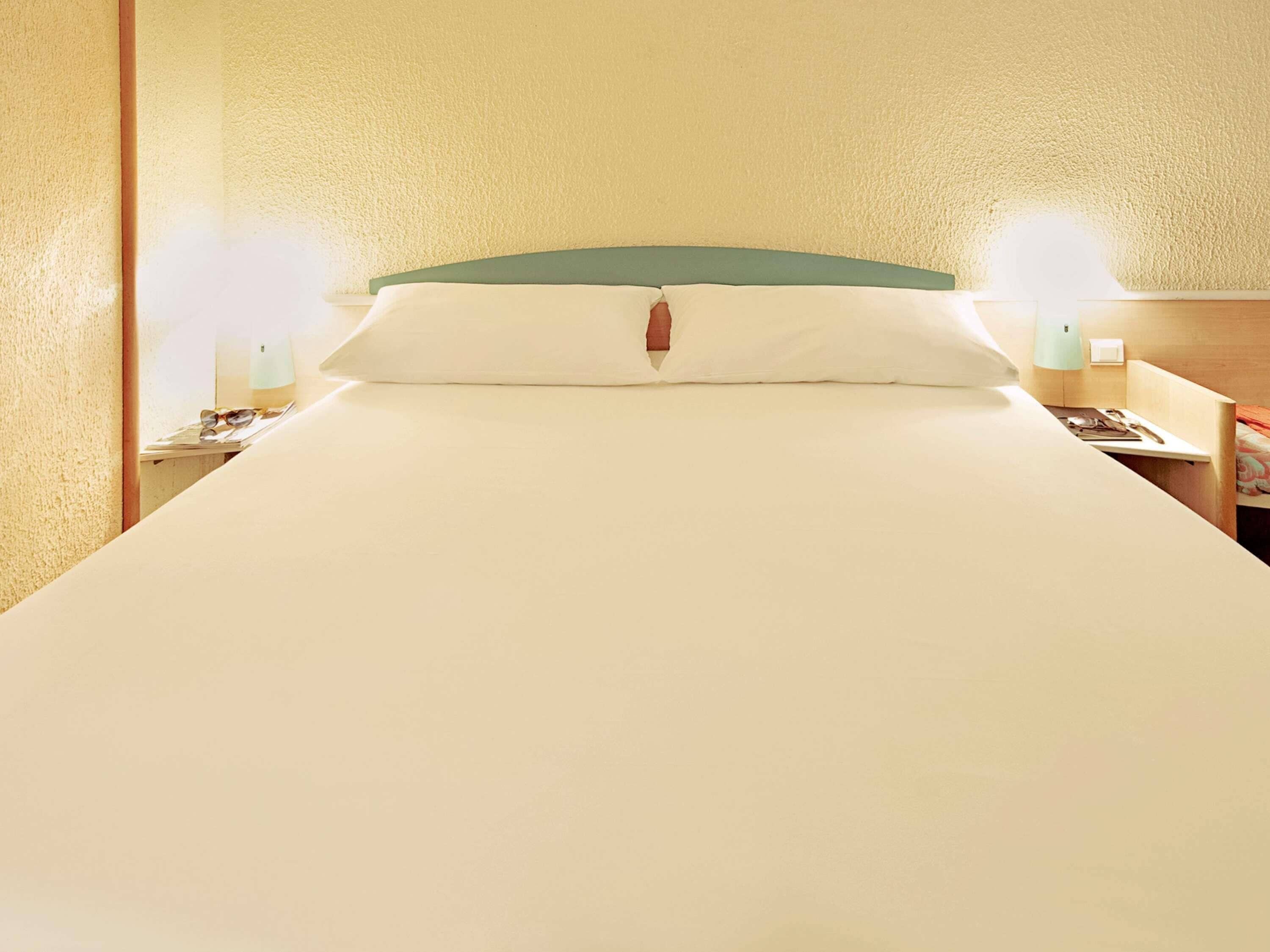 Ein Hotelzimmer mit einem großen Bett, zwei Nachttischen und einem Schreibtisch.