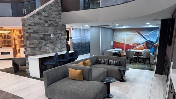 A modern hotel lobby with a sectional sofa, a stone accent wall, and a mural.