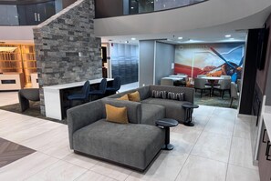 A modern hotel lobby with a sectional sofa, a stone accent wall, and a mural.