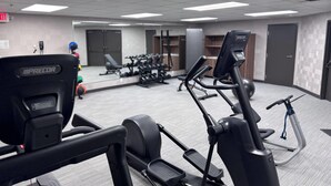 A gym with exercise equipment, a mirror, and a door in the background.