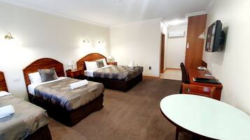 Ein Hotelzimmer mit zwei Betten, einem Schreibtisch, einem Stuhl, einem Fernseher und Teppichboden.