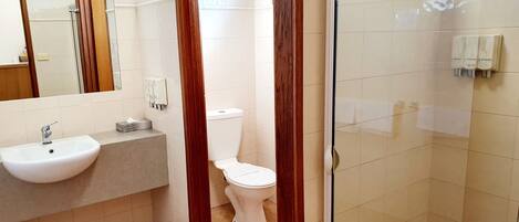 Un baño con lavamanos, inodoro y cabina de ducha de vidrio.