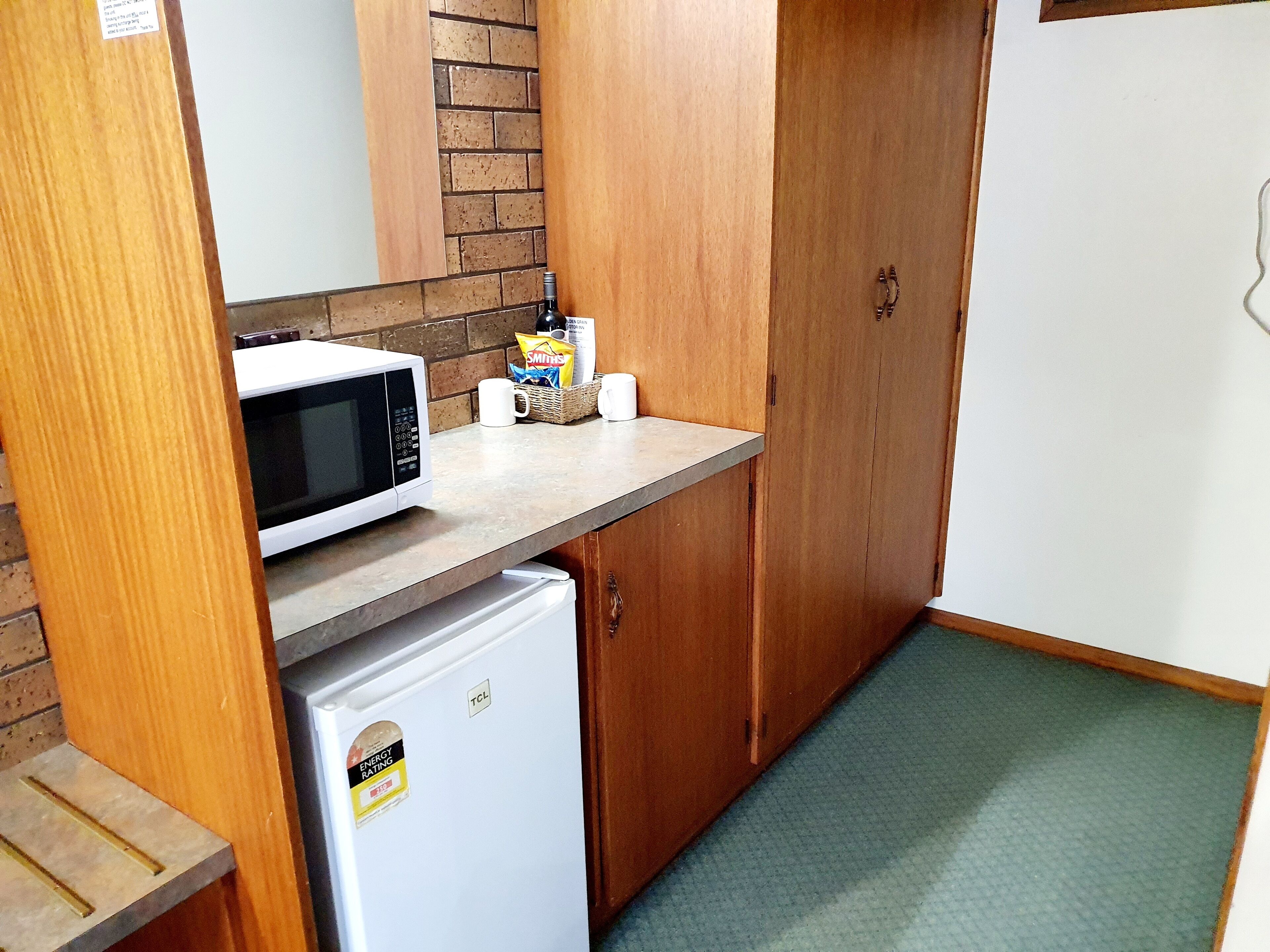 A compact kitchenette with a microwave, a small refrigerator, and a wooden cabinet.