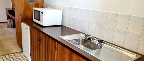 Una cocina con un lavamanos de acero inoxidable, un microondas y armarios de madera.