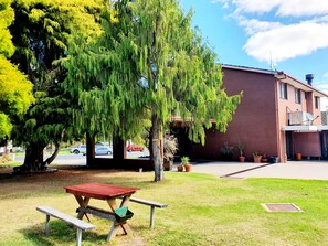 A picnic table in a grassy area with a building in the background.