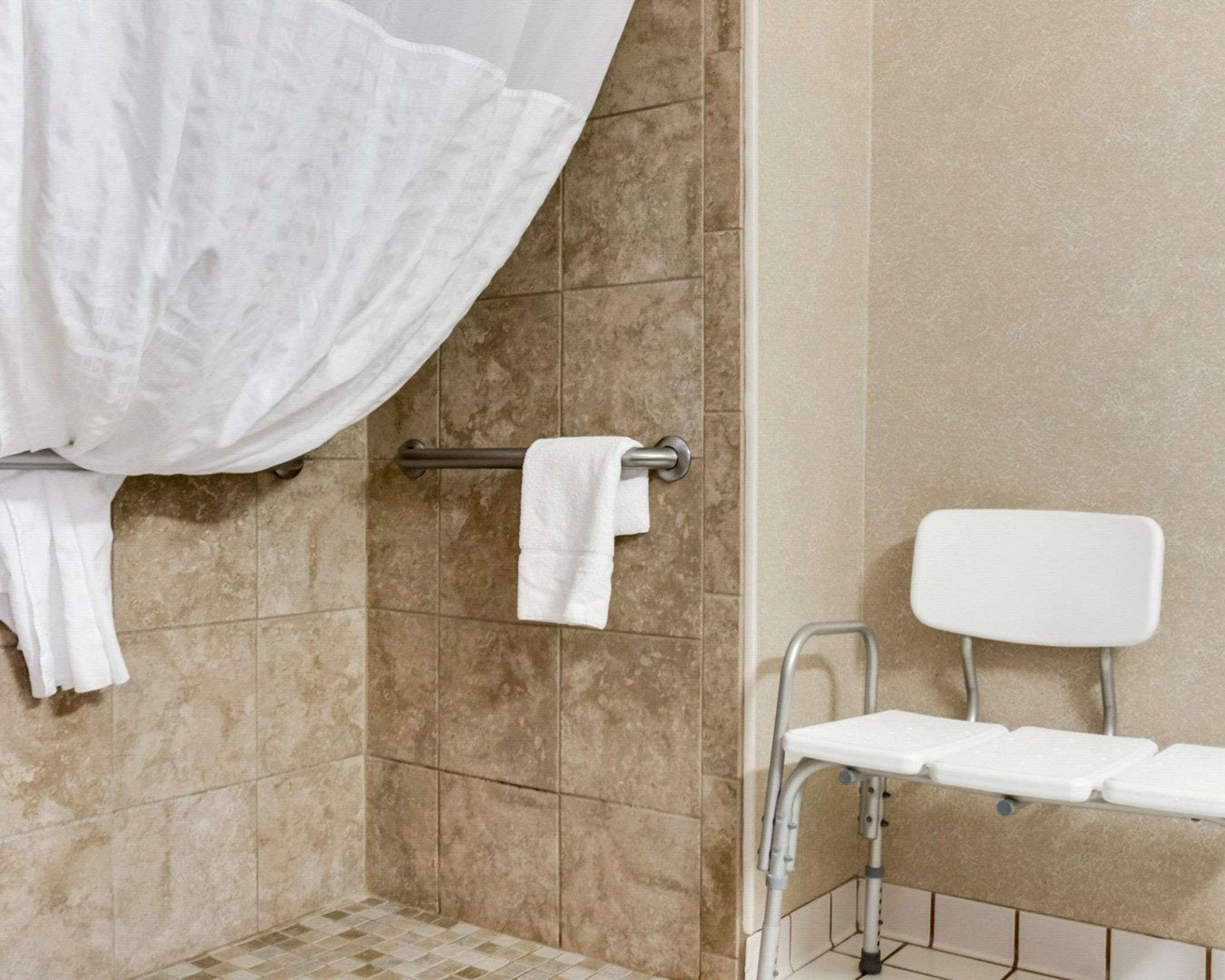 A bathroom with a shower area, a towel rack, and a white toilet.
