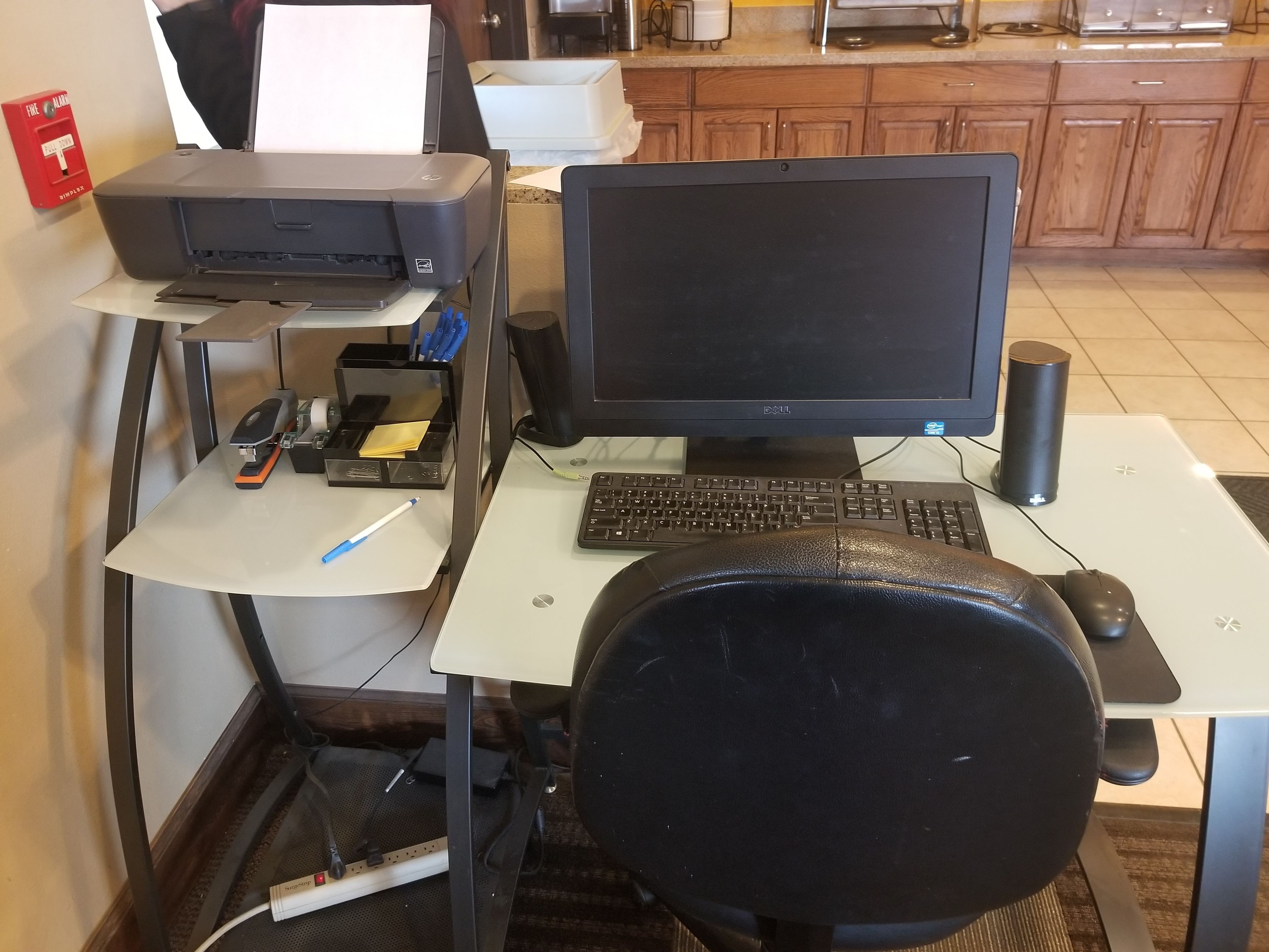 A home office setup with a desktop computer, keyboard, mouse, and a printer on a desk.