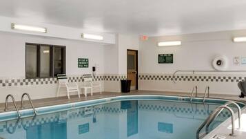 A swimming pool with a checkered tile border, a lifeguard chair, and a sign indicating a 9-1-1 emergency number.