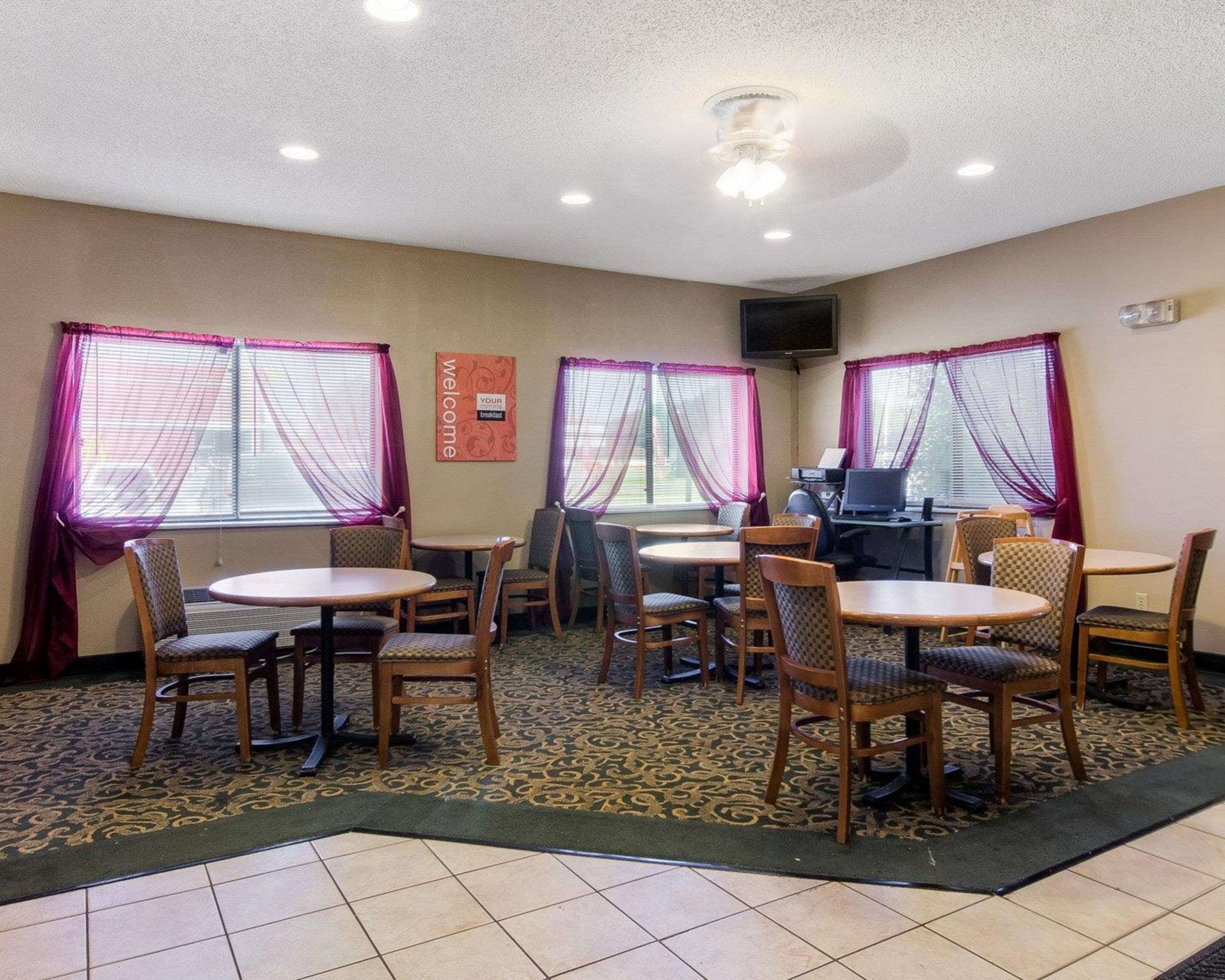 A dining area with round tables and chairs, a television, and a 'Welcome' sign.