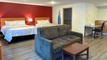 A hotel room with two beds, a sofa, a small table, a desk, and a chair.
