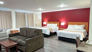 A hotel room with two beds, a sofa, a small table, and a desk with a telephone. - Econo Lodge Edmonds North Seattle (Edmonds)