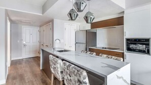 A modern kitchen with a marble island, bar stools, stainless steel appliances, and pendant lighting. - Hilton Grand Vacations Club Flamingo Las Vegas (Las Vegas)
