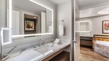 A modern bathroom with a large mirror, a sink, and a bathtub.