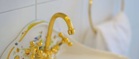 Ein Badezimmer mit einem goldenen Wasserhahn und einem Zierbecken.