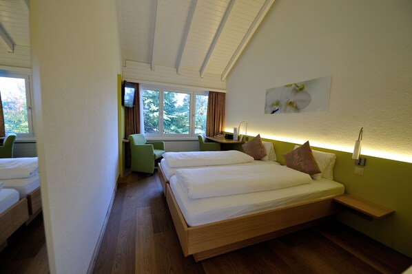 A hotel room with a large bed, a desk, a chair, and a TV.